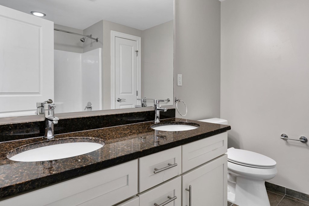 A bathroom with a sink, toilet, and mirror.