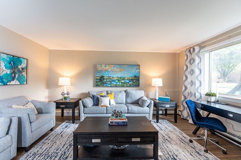 A living room with a grey couch, a black coffee table, and a painting on the wall.
