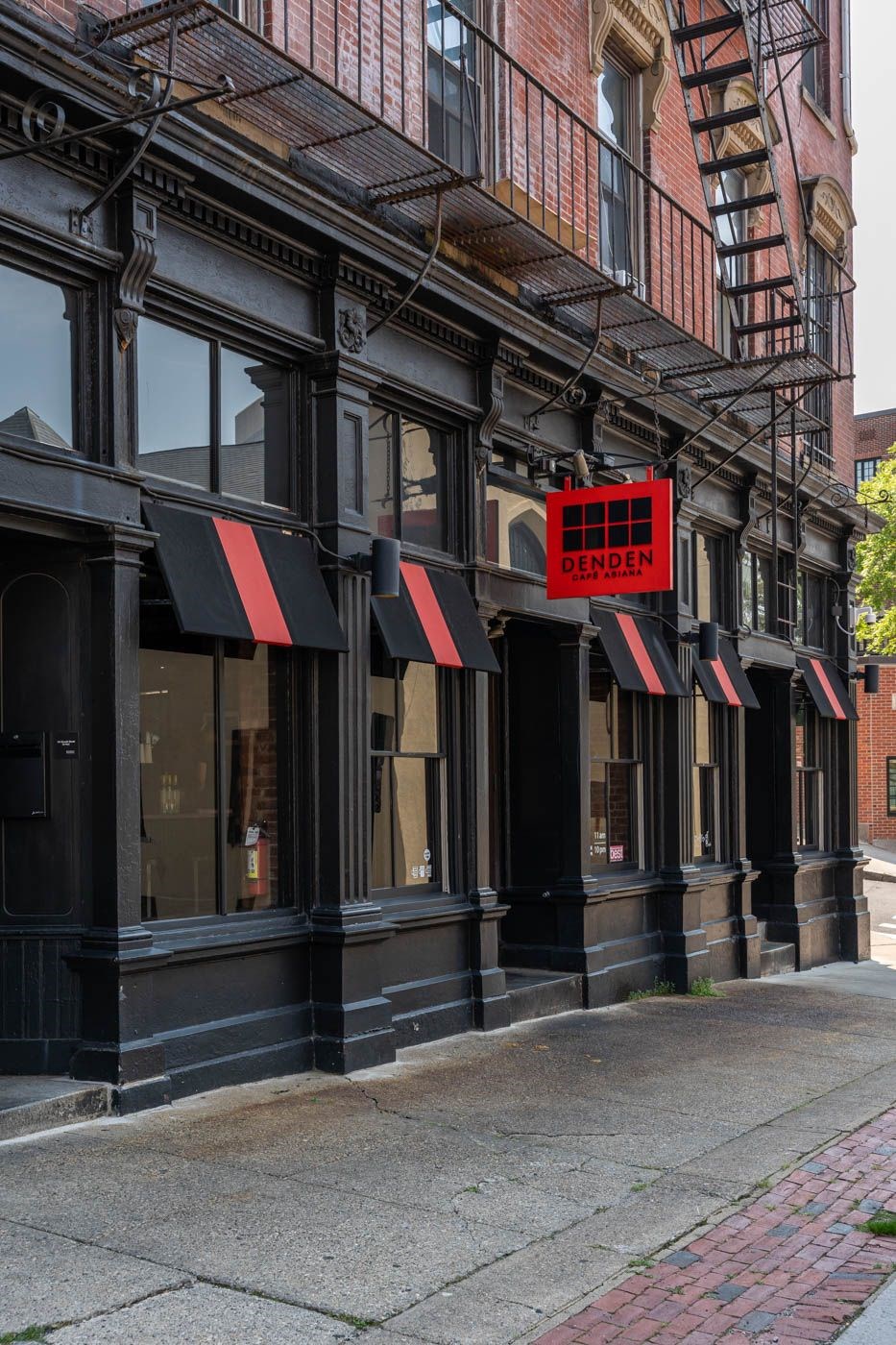 A black building with a red sign that says DENDEN cafe