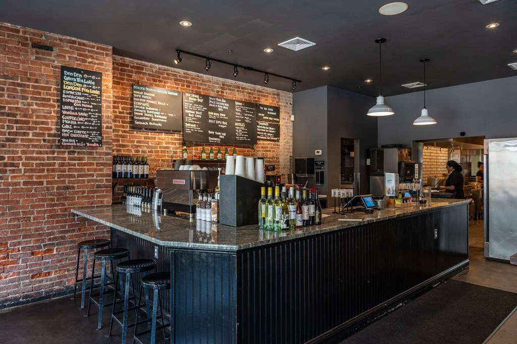 A bar with a black counter and a brick wall.