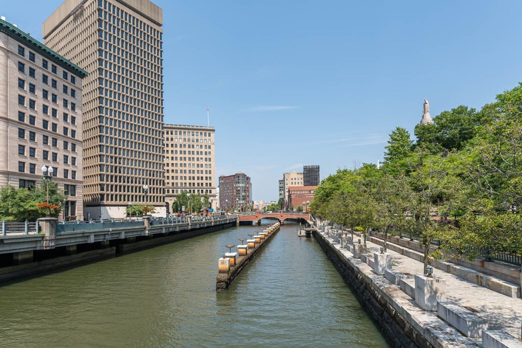 The Providence riverwalk with a boat and buildings on both sides.