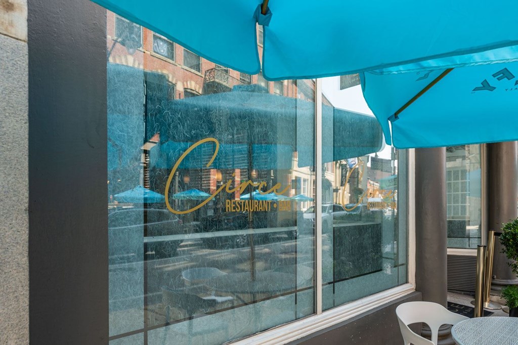 A blue umbrella is covering a table outside of a restaurant.