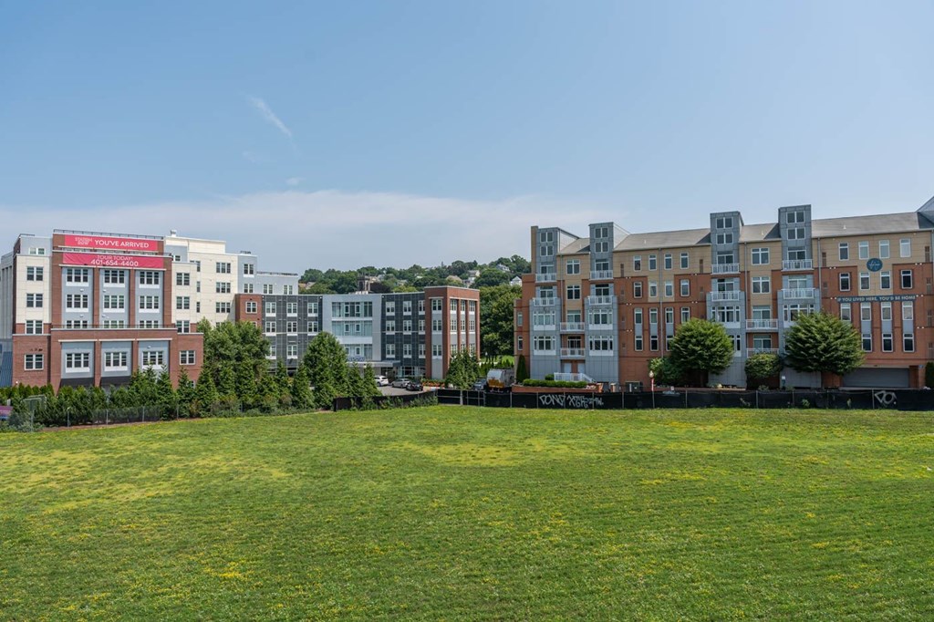A grassy field in front of apartment buildings.