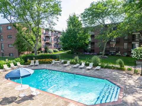 a swimming pool with chairs and an umbrella in front of an apartment building