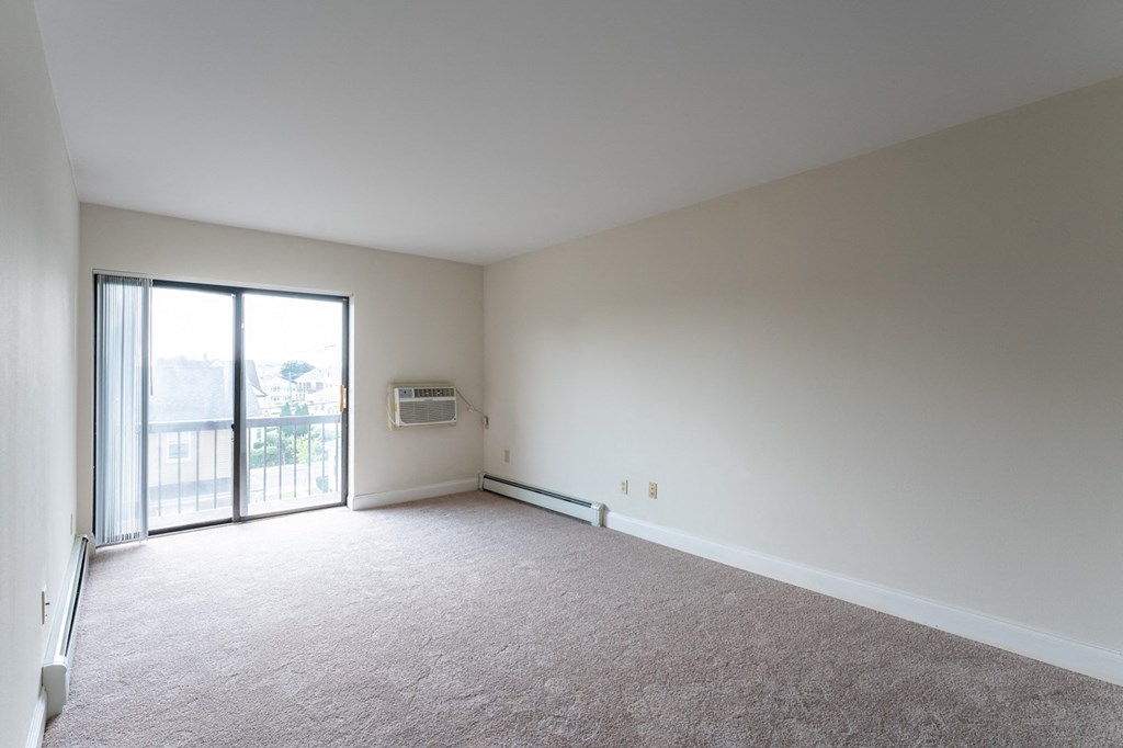 an empty living room with a sliding glass door to a balcony