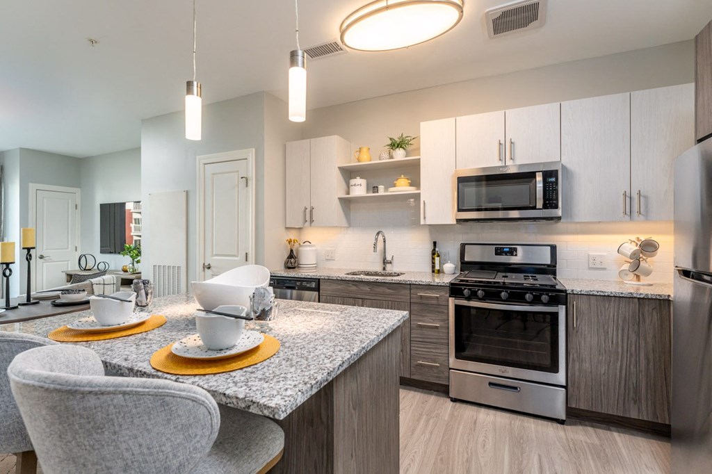 One bedroom model apartment with overhead and undercabinet lighting, granite countertop, kitchen island, stainless appliances