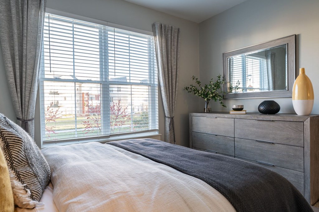 Model apartment bedroom with large windows overlooking courtyard