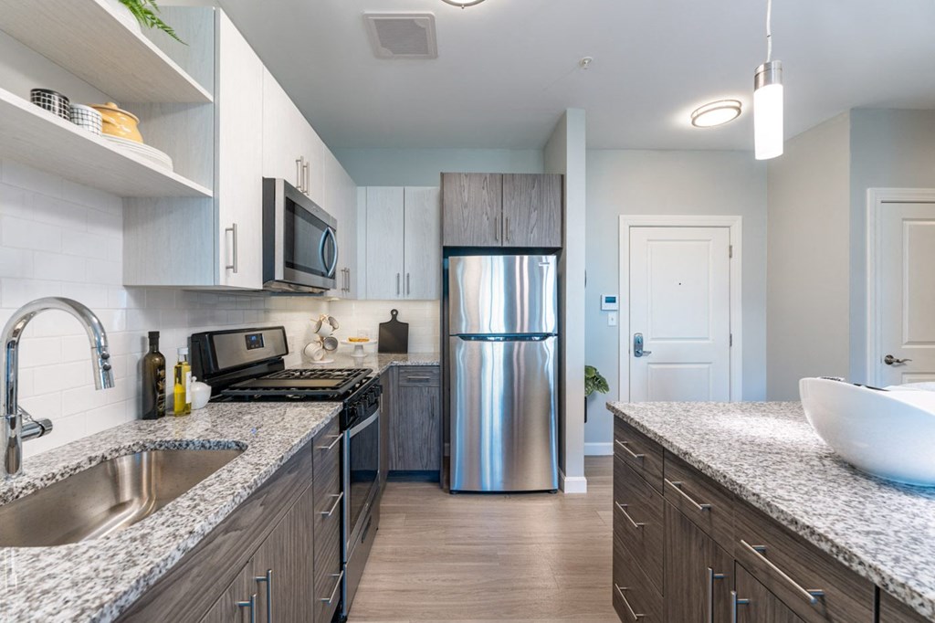 model apartment kitchen and granite counters, stainless steel appliances.