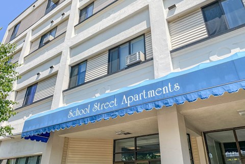A building with a blue awning that says School Street Apartments.