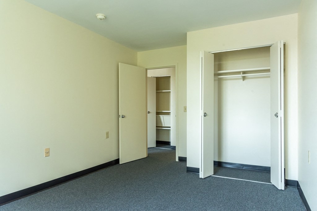 A hallway with white walls and a grey carpet.