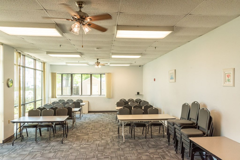 A room with tables and chairs and a ceiling fan.
