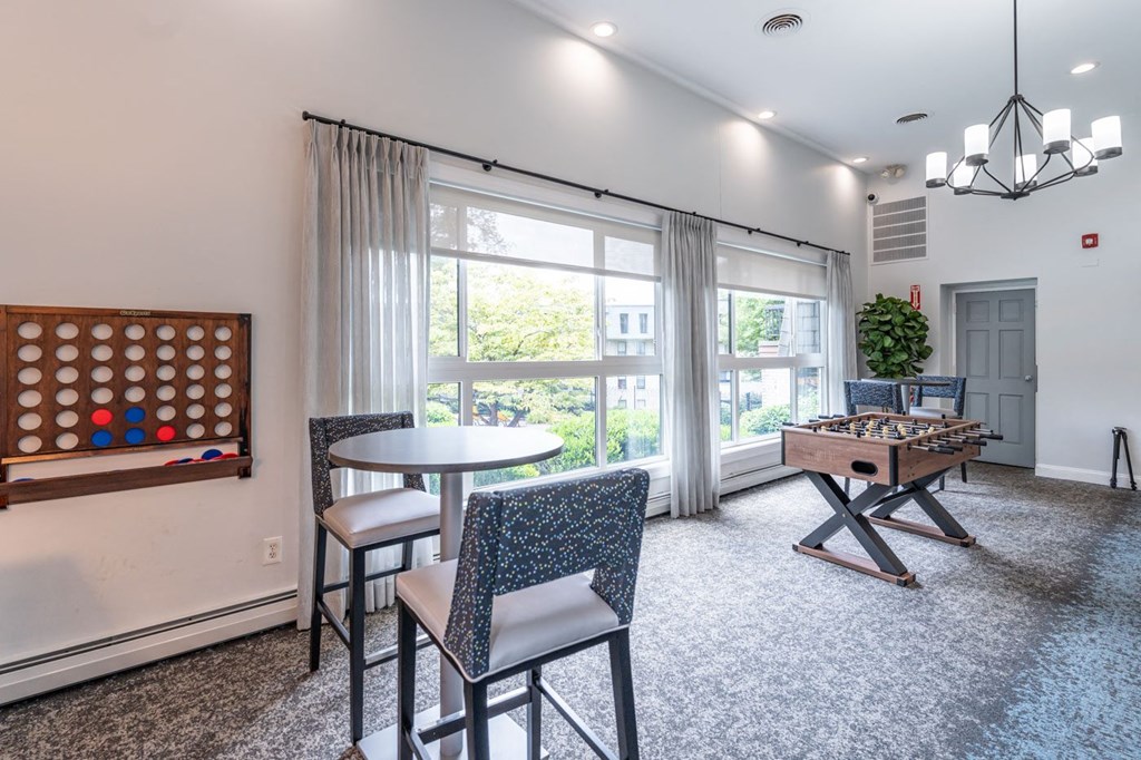 a living room with a game table and chairs and a window
