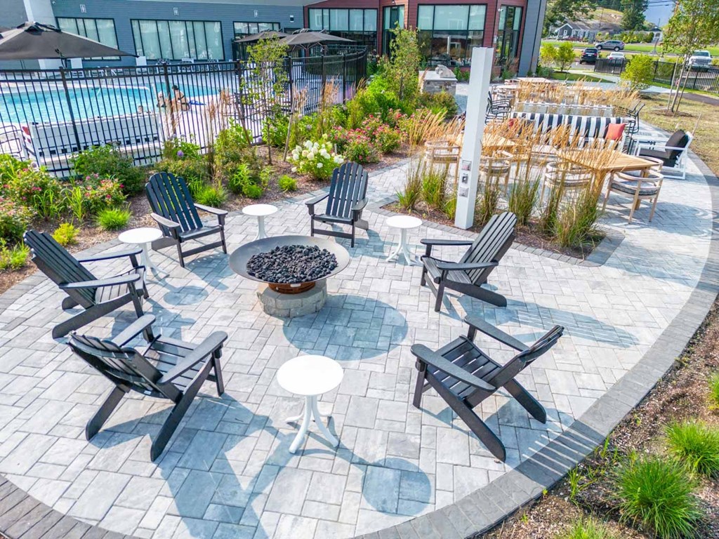 a fire pit surrounded by chairs on a patio in front of a building