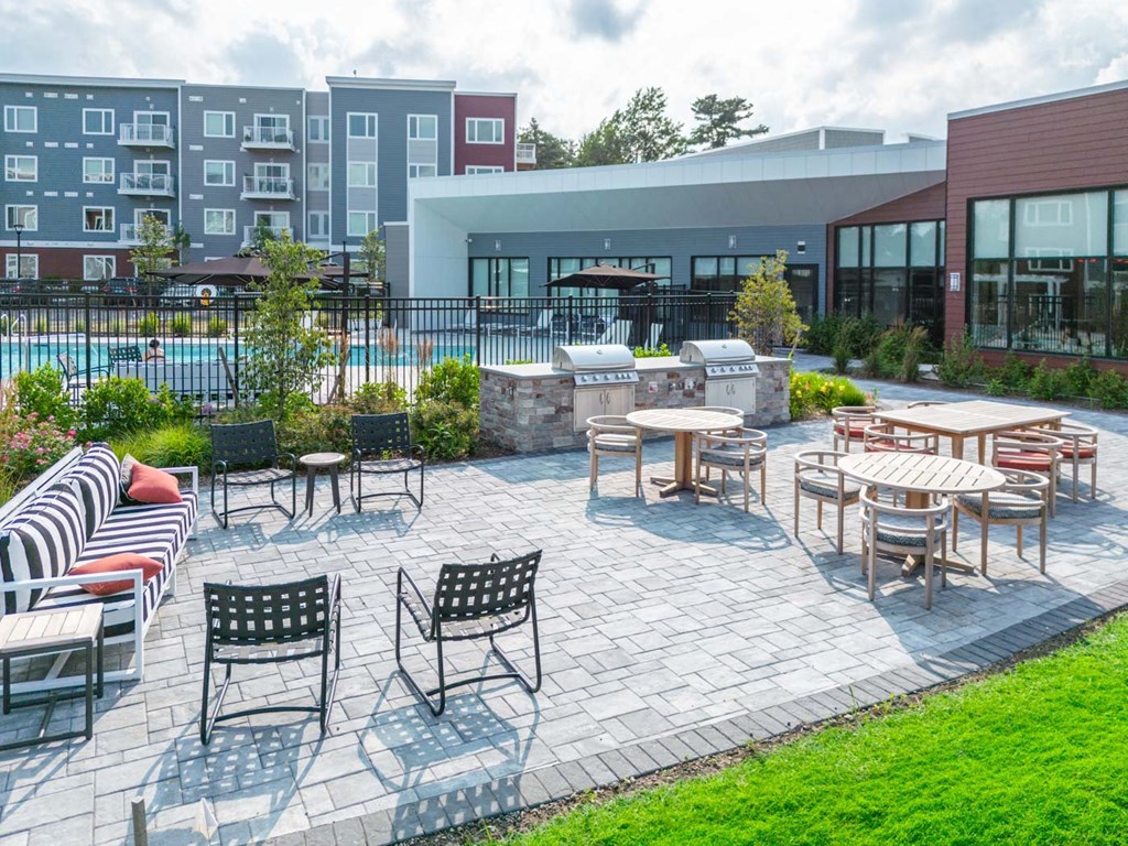 a patio with tables and chairs and a pool in the background