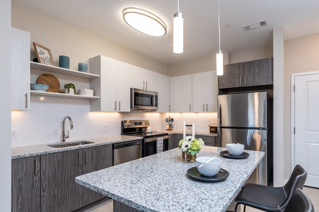The Curtis kitchen with granite counters, electric range, stainless appliances, and island counter