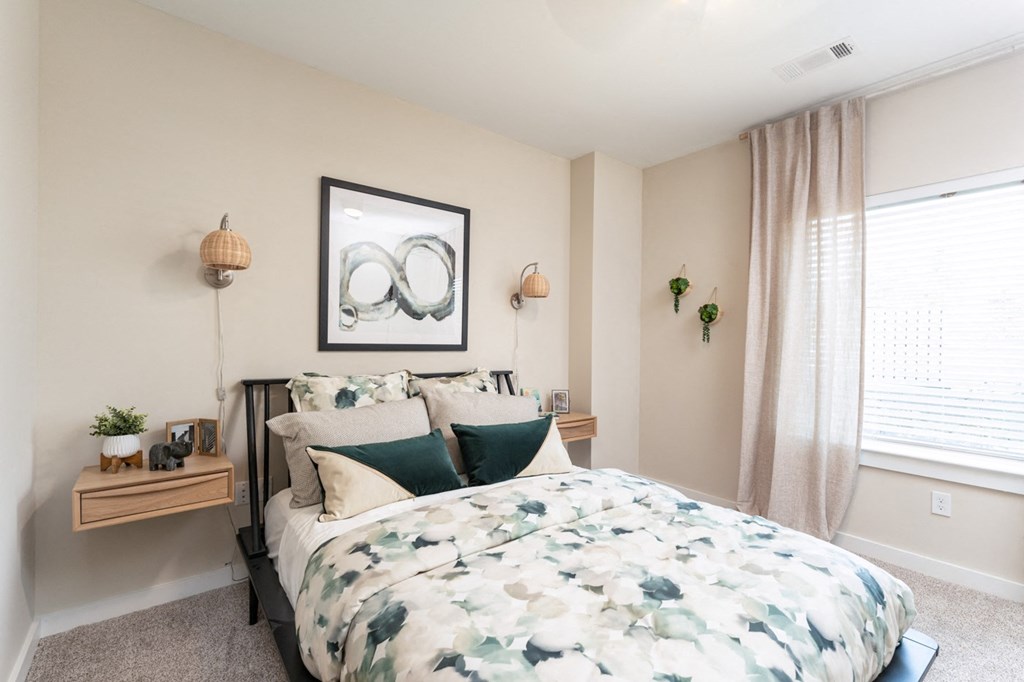 The Curtis Model Apartment Bedroom with plush carpeting and large window
