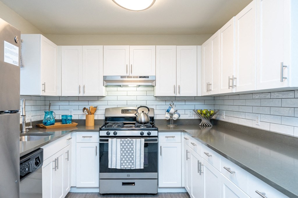a white kitchen with stainless steel appliances and white cabinets