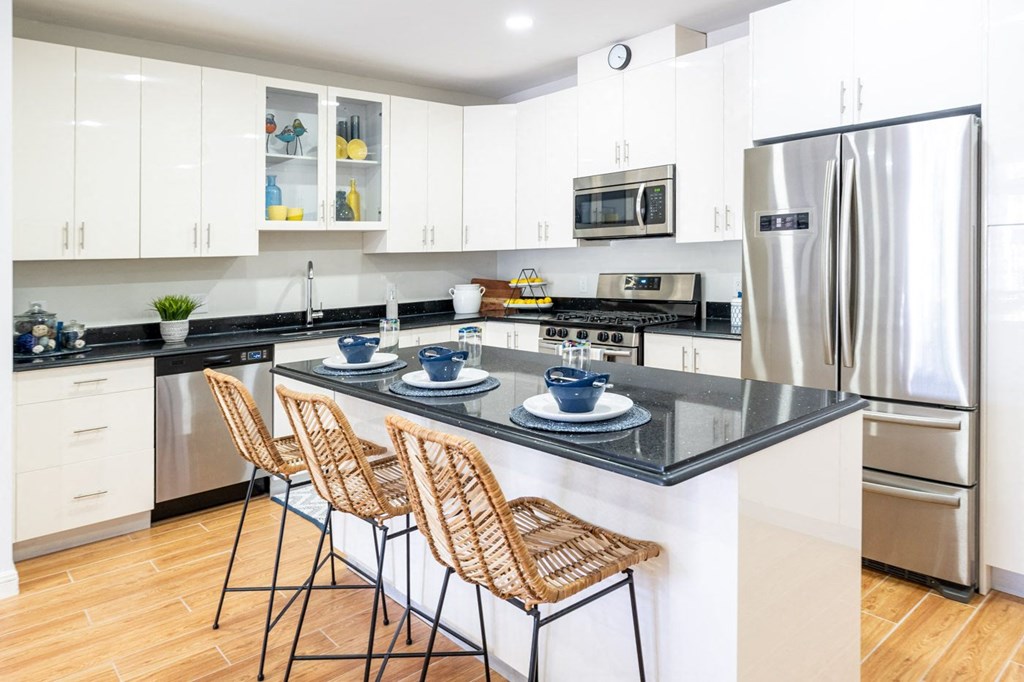 The sto one bedroom kitchen with black granite countertop, stainless appliances, and white vibrant cabinetry