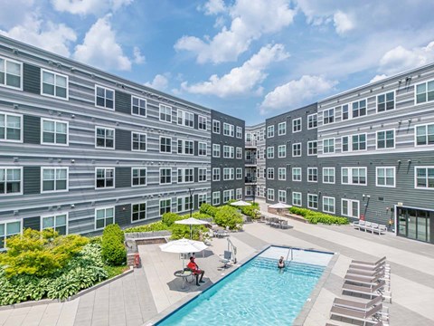 A large swimming pool surrounded by lounge chairs and umbrellas in the middle of a courtyard at The Val