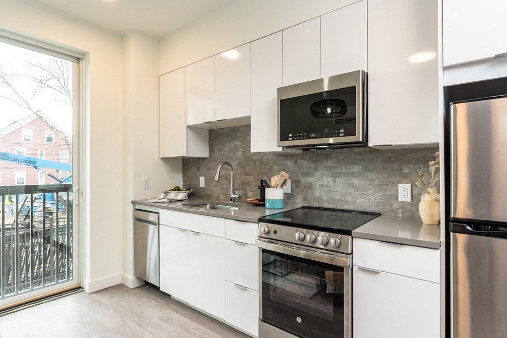 a kitchen with white cabinets and stainless steel appliances at Union 346 Apartments, Somerville