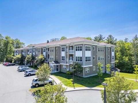 A large apartment complex with a parking lot in front.