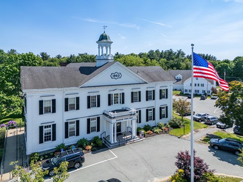 A white building with a green dome and an American flag on top.