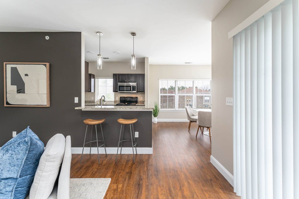 A modern kitchen with a bar stool and a dining table.