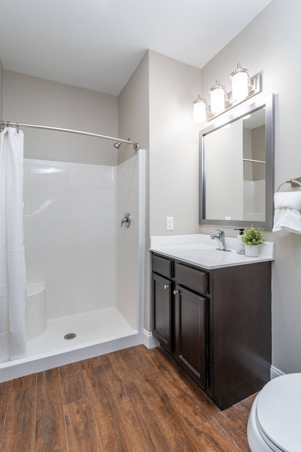 A bathroom with a white sink, a white toilet, a black cabinet, and a white shower.