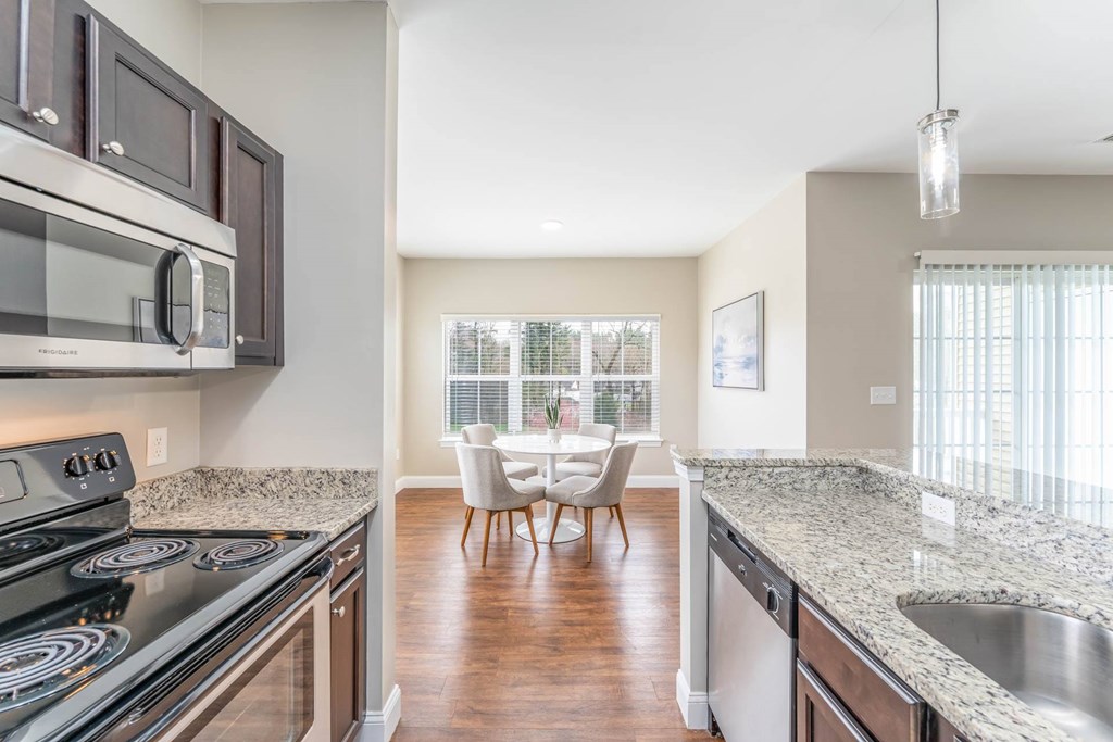 A kitchen with granite countertops and a dining area with a table and chairs.