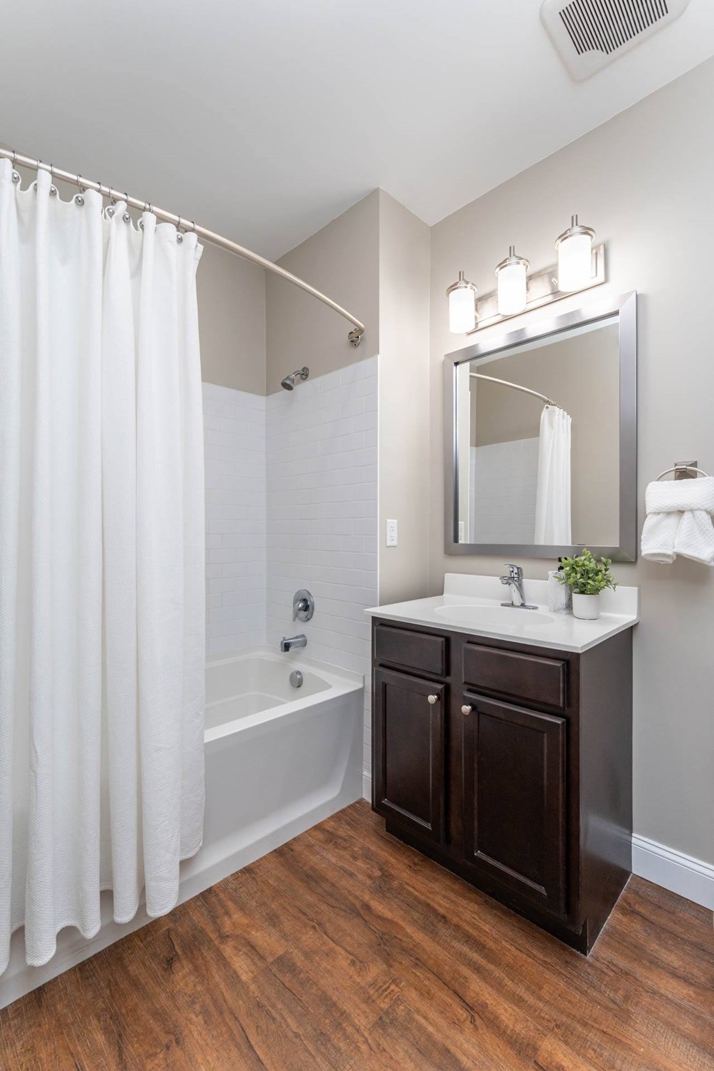 A white shower curtain hangs over a white bathtub in a bathroom.