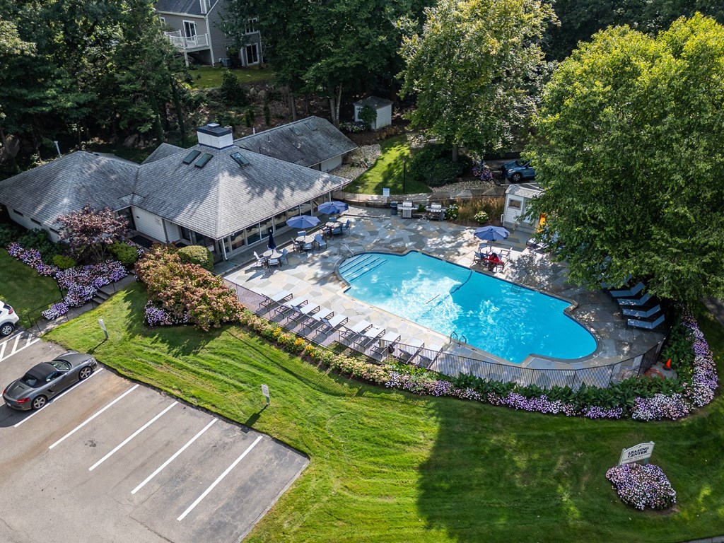 an aerial view of a swimming pool in a backyard with a pavilion and lawn