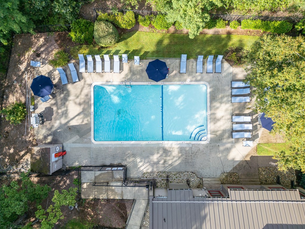 an aerial view of a pool with umbrellas and chairs around it