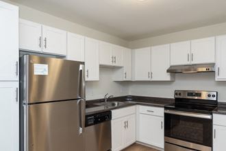 Adams Village apartments kitchen with white cabinets and stainless appliances