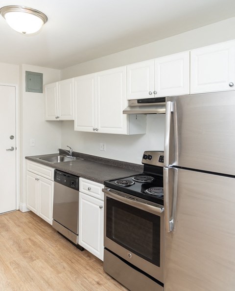 A kitchen with white cabinets and a black fridge.