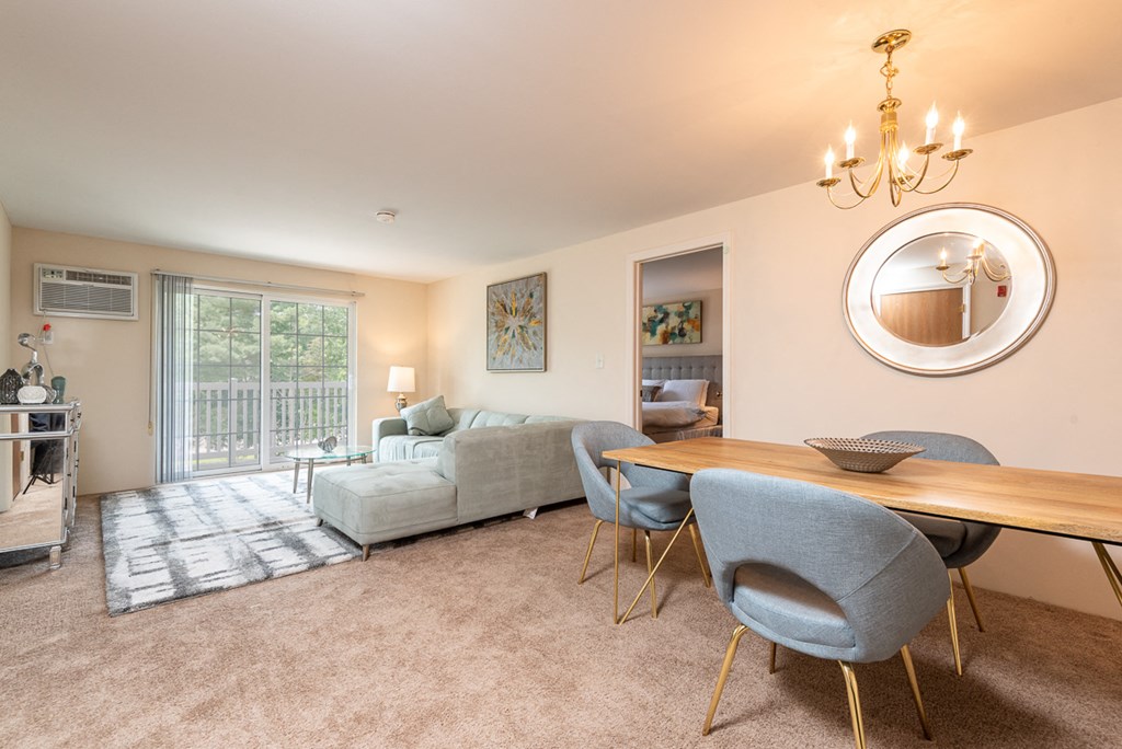 Two bedroom common area living room with balcony and dining space with plush carpeting