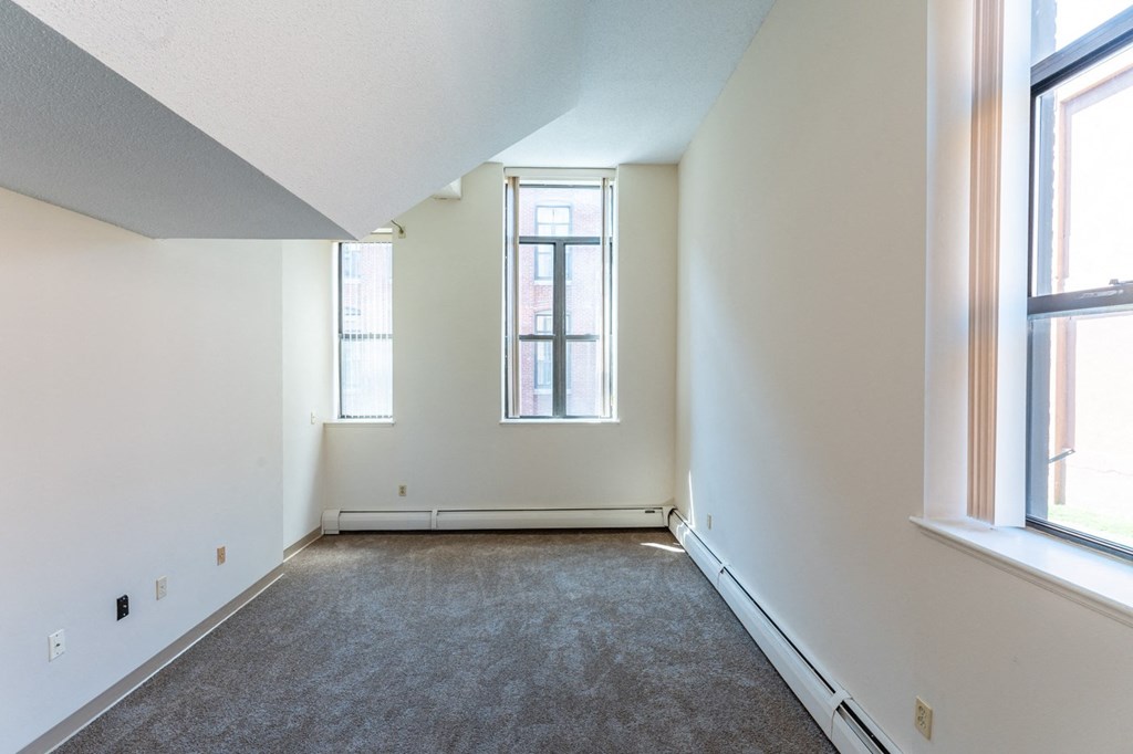 an empty room with two windows and a carpet