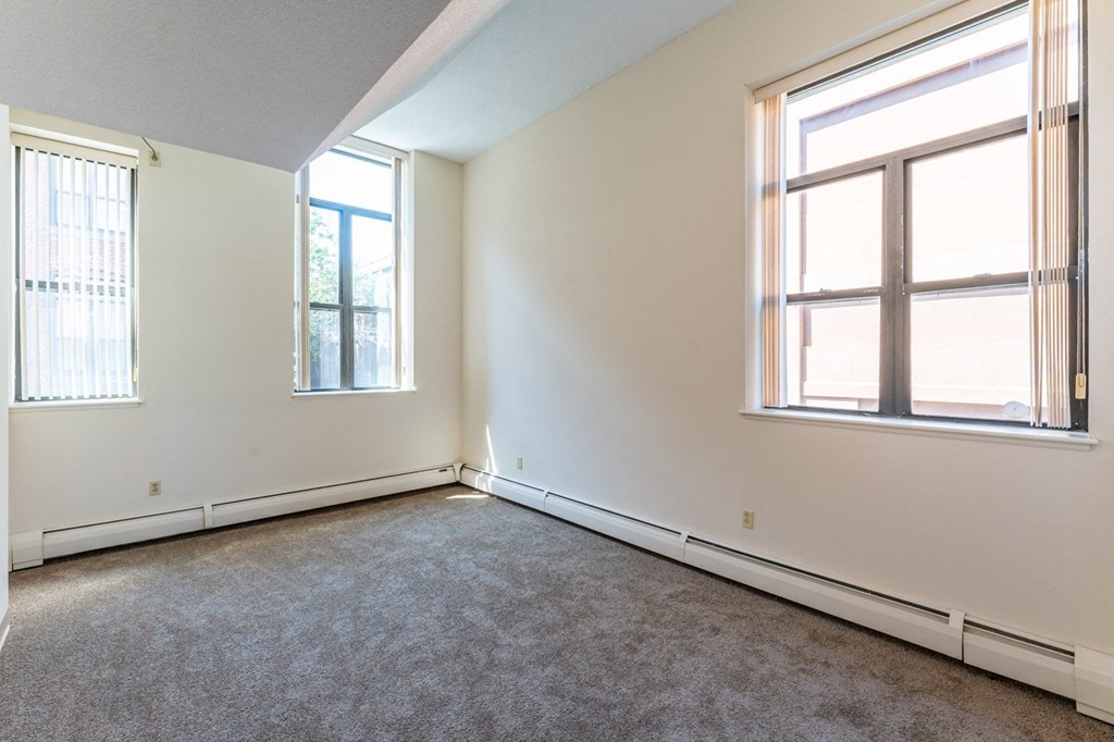 an empty room with two windows and a carpet