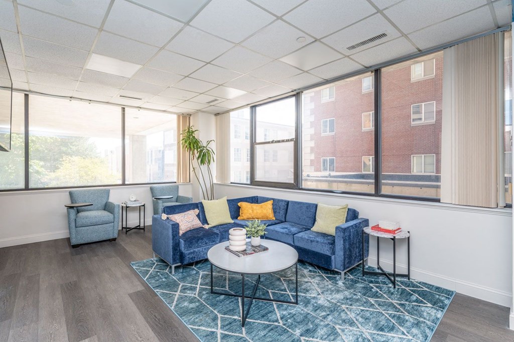 a living room with blue couches and a coffee table in front of large windows