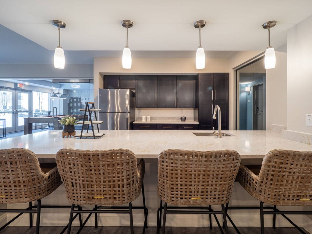 A chic kitchen area with bar seating, pendant lights, and stainless steel appliances.