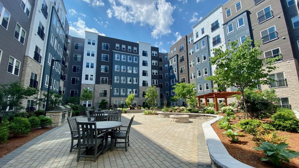 A beautifully landscaped courtyard featuring outdoor dining tables and lush greenery.