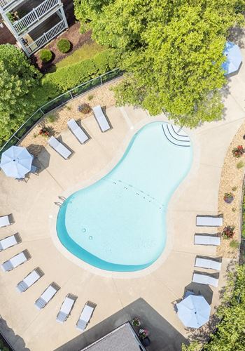 an overhead view of a swimming pool with chairs and umbrellas