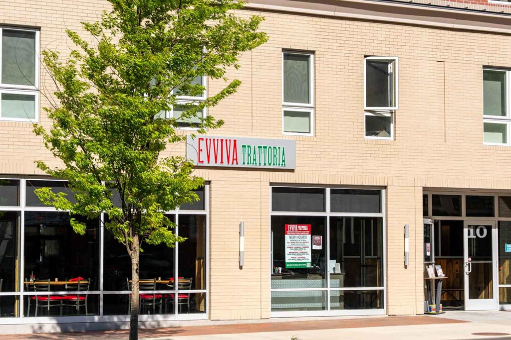A building with a tree in front of it and a sign that says EVVIVIA TRATORIA.