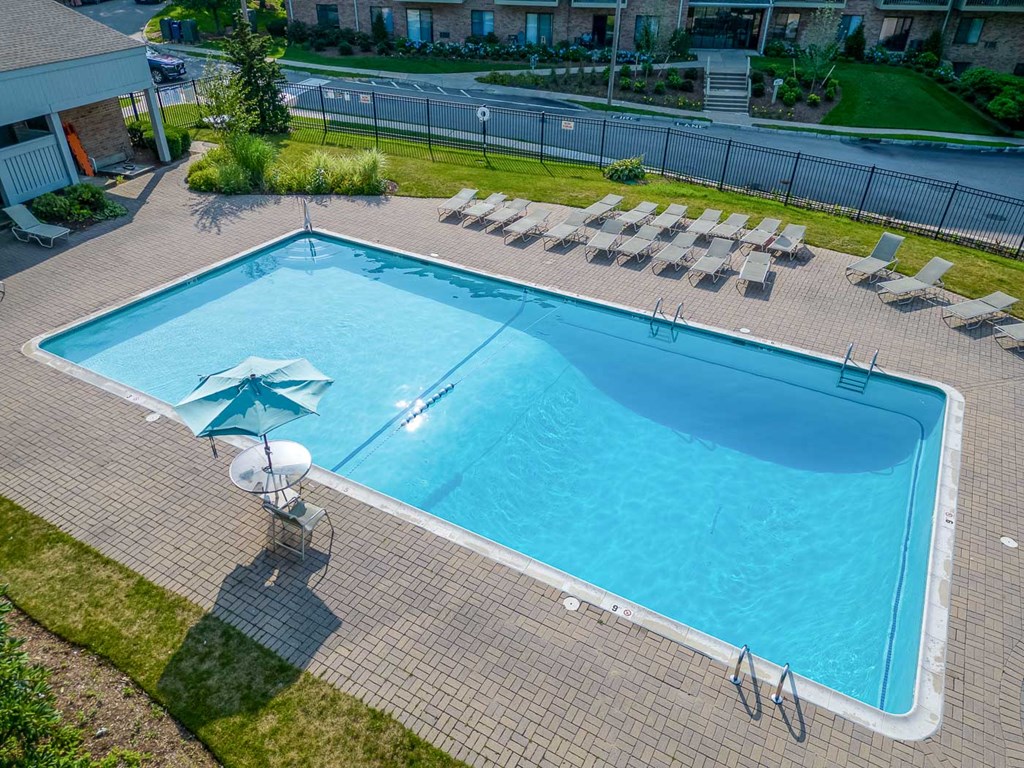 an aerial view of a large swimming pool with lounge chairs and an umbrella