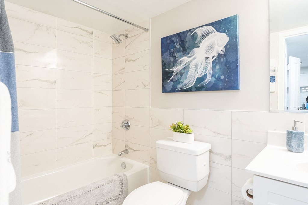 a bathroom with a white tub and toilet and a painting of a white jellyfish