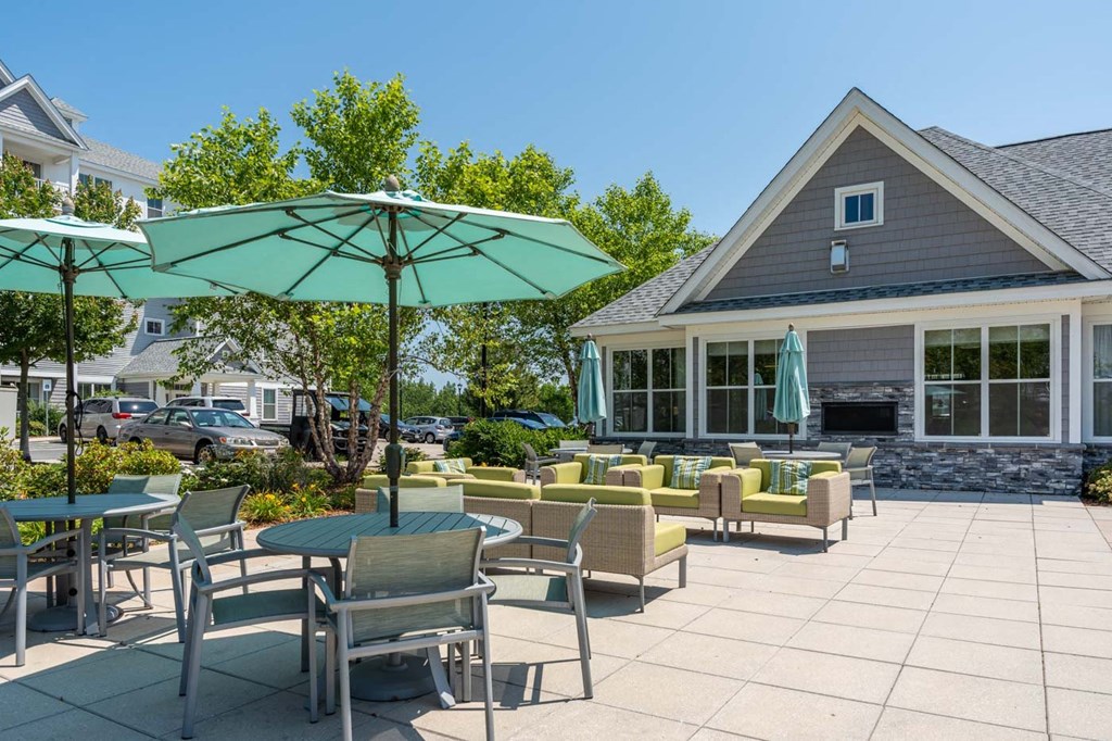 a patio with tables chairs and umbrellas outside of a building