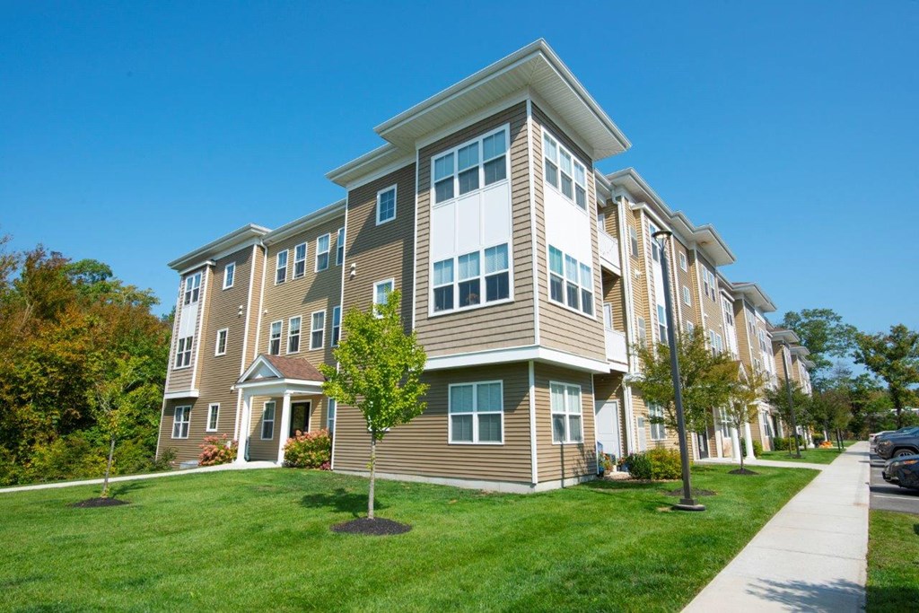A sleek, multi-level apartment complex surrounded by manicured landscaping at Webster Woods.