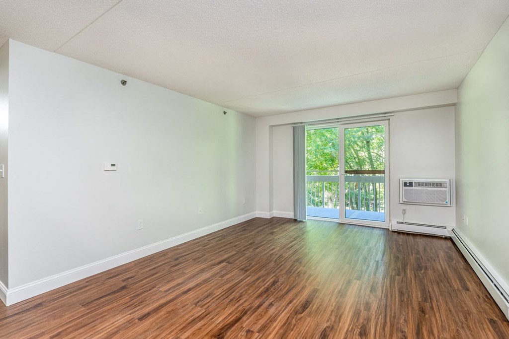 an empty living room with wood floors and a door to a balcony