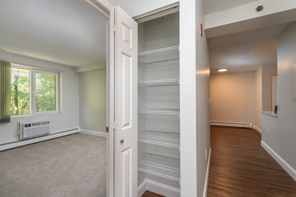 an empty living room with an open door to an empty closet