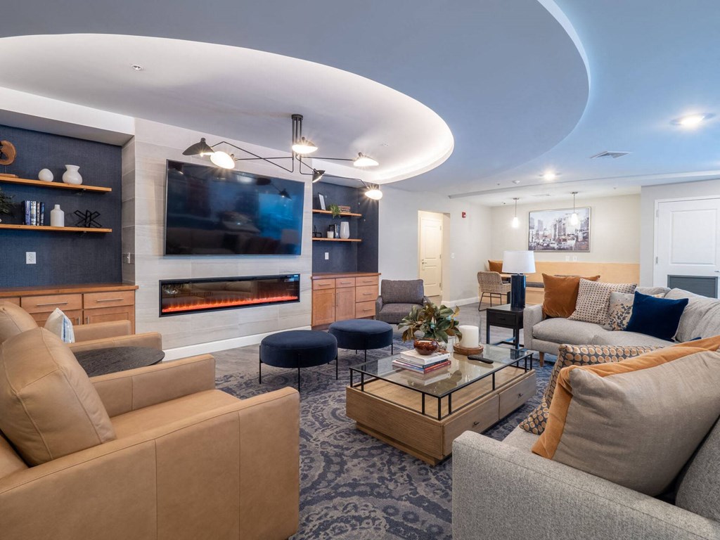 A contemporary social lounge with cozy seating arrangements, a fireplace, and a TV.