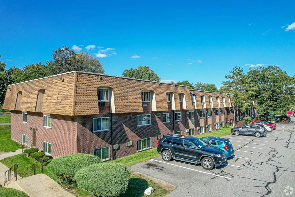 A brick building with a parking lot in front.
